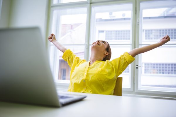 Excited businesswoman with outstretched arms at office